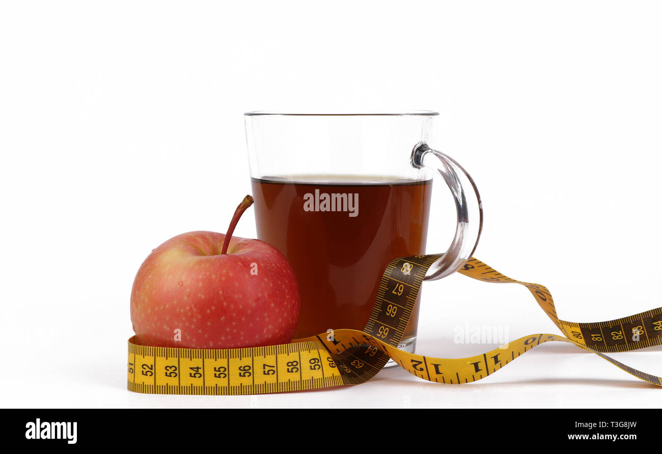 L'amaigrissement avec du thé et des fruits, une tasse de thé et un ruban à mesurer et un délicieux pomme rouge isolé sur fond blanc Banque D'Images