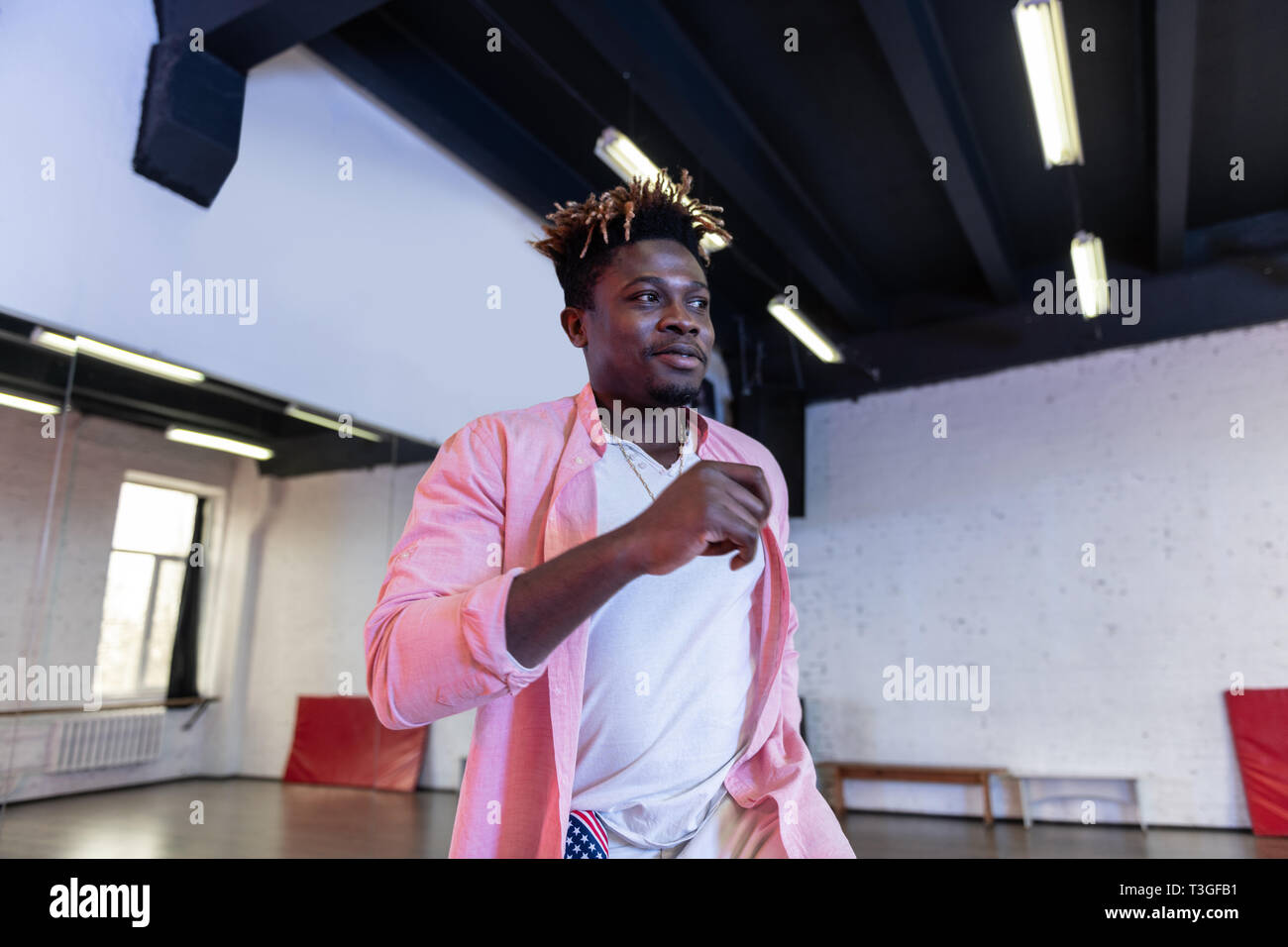 Cheerful beau jeune homme avec des dreadlocks court portant chemise rose Banque D'Images