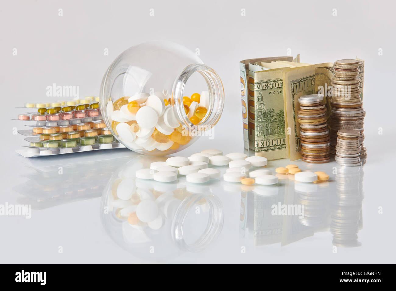 Pack de médecine pills avec trois paquets de pièces et le flacon en verre avec de l'argent en dollars sur une table en verre blanc avec reflet miroir Banque D'Images