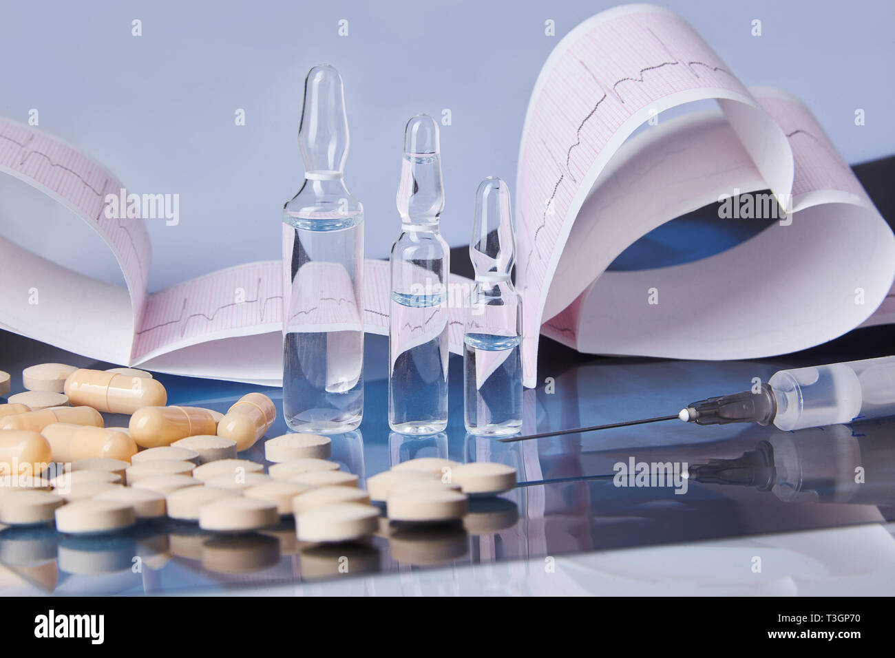 Dispersés gélules, comprimés, ampoules et la seringue sur la table avec cardiogramme (tableau i) et l'ecg roentgen. Concept de soins de santé. Cardiogramme impression. Banque D'Images