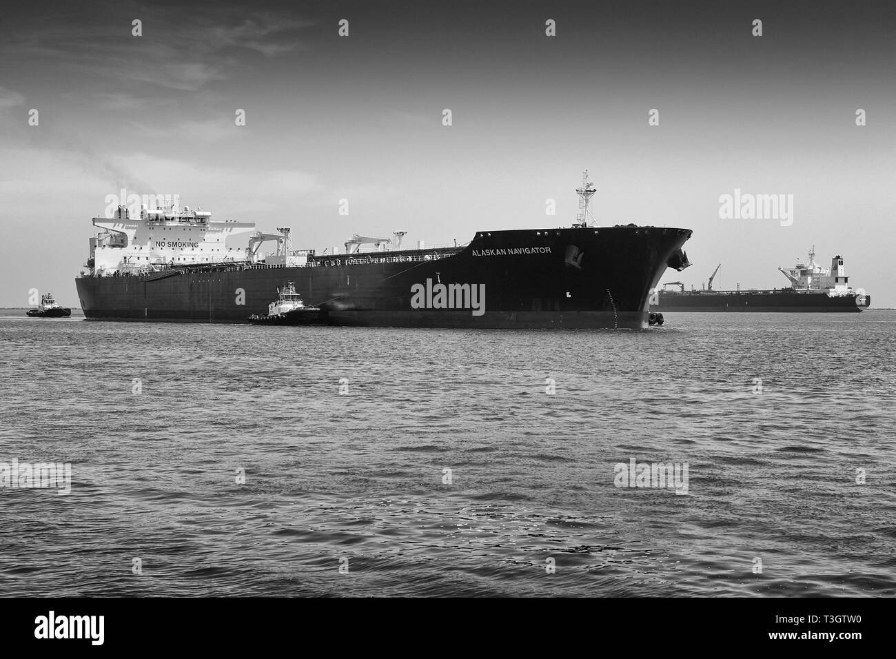 Photo en noir et blanc de Foss Maritime Tugboats guidant le superpétrolier, ALASKAN NAVIGATOR, alors qu'il entre dans le port de long Beach, Californie, États-Unis Banque D'Images