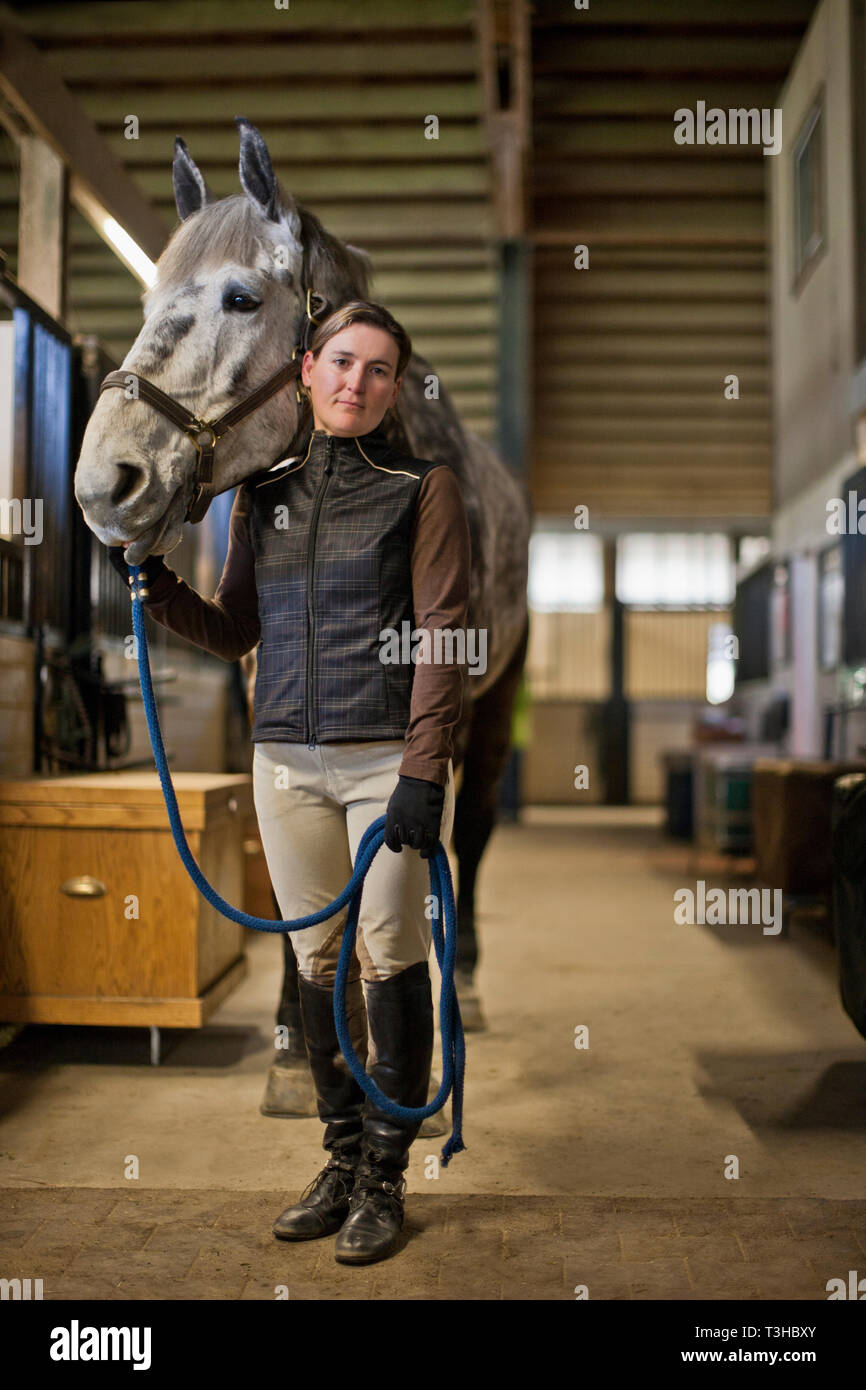 Portrait of a Mid adult woman et son cheval dans une étable. Banque D'Images