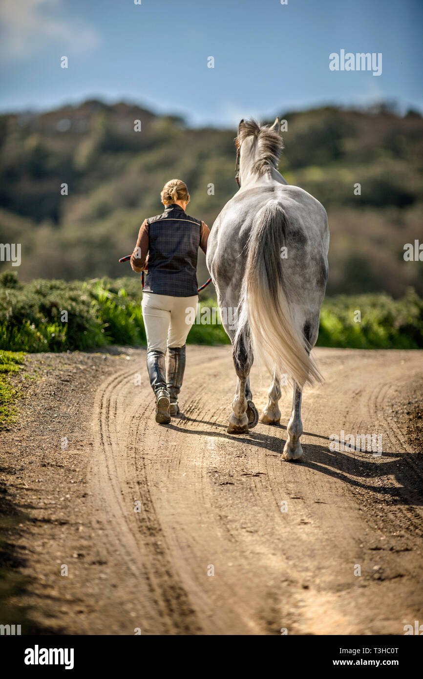 Femme menant son cheval sur un chemin rural. Banque D'Images