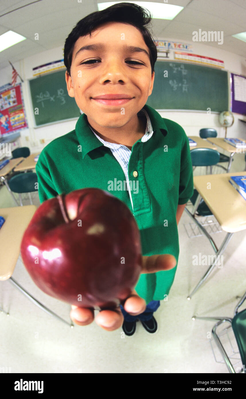 Un très fier Hispanic élève est titulaire d'un apple en face de son professeur Banque D'Images