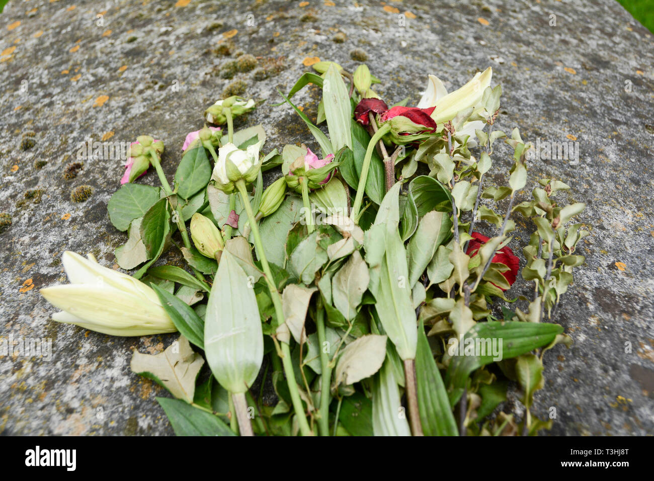 Les fleurs fanées se reposant sur une tombe dans un cimetière anglais Banque D'Images