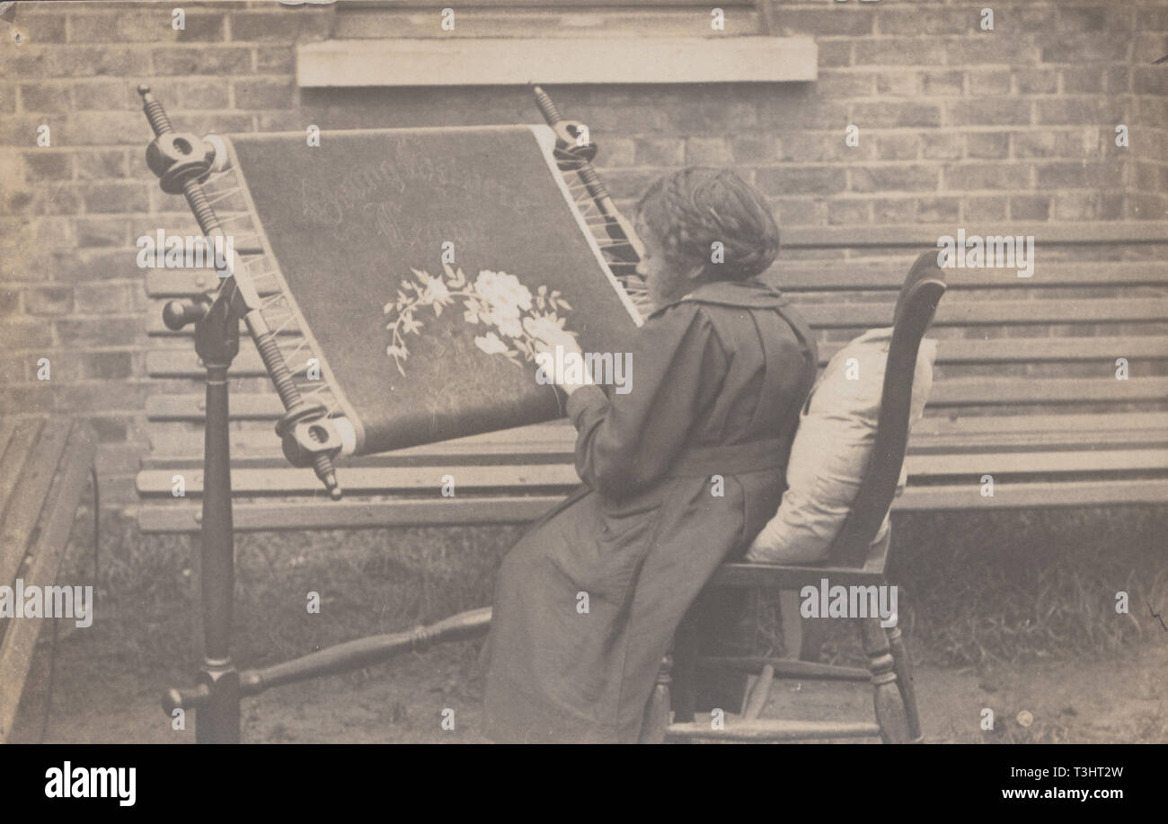 Vintage Carte postale photographique montrant un enfant assis à l'extérieur Cross Stitching Banque D'Images