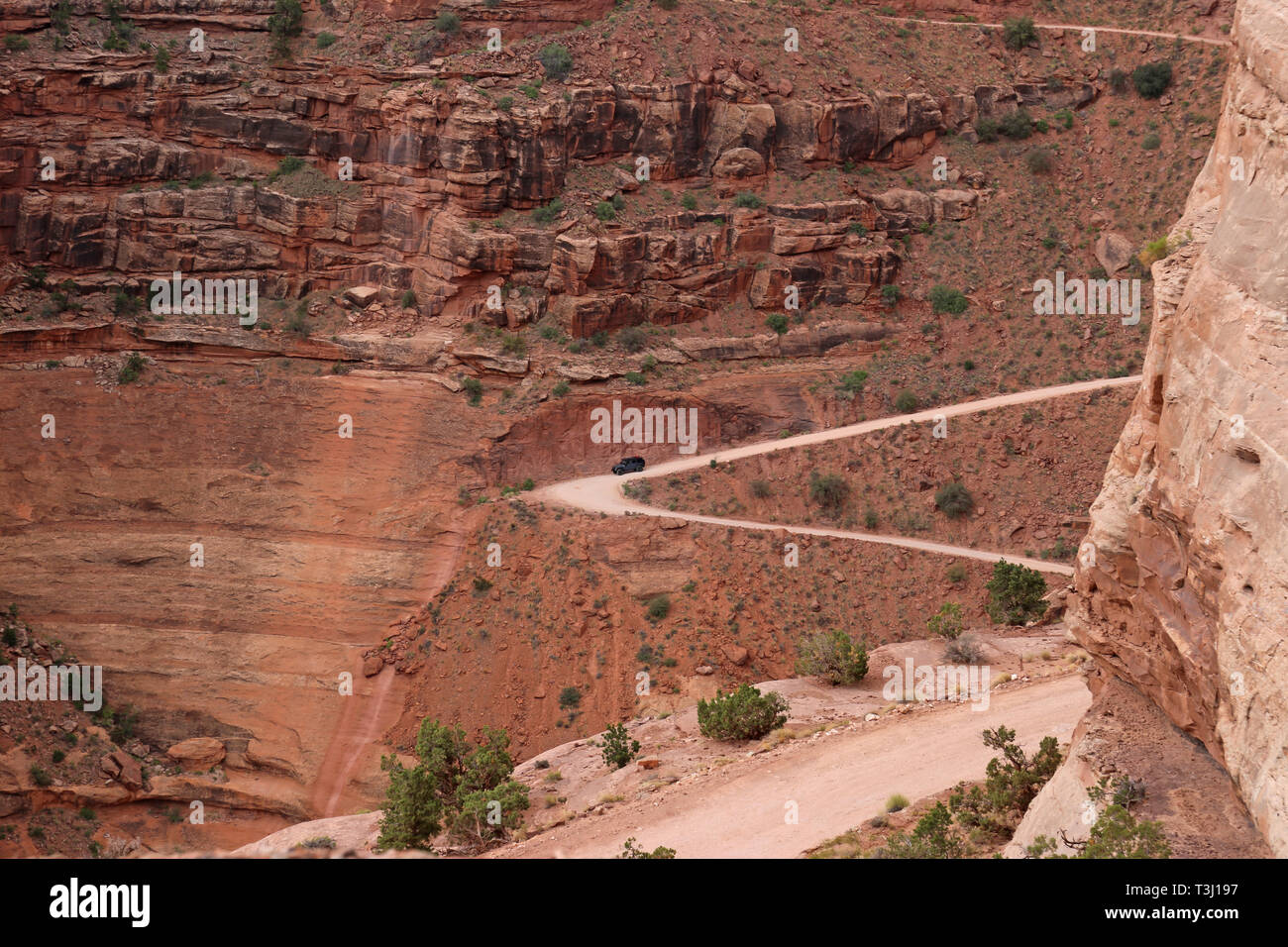 Une jeep conduite le long Shafer Canyon Road tournant à droite sur le côté d'une falaise, dans le Parc National de Canyonlands, Utah. Banque D'Images