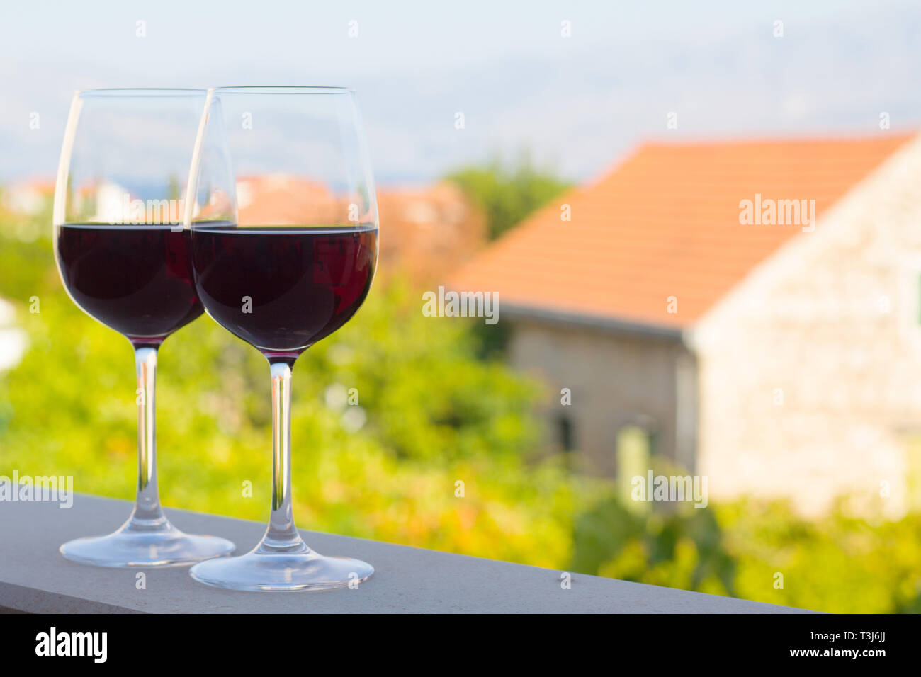 Deux verres de vin rouge à Terrace patio avec vue sur la ville un arrière-plan en Croatie Supetar , concept vin naturel croate Banque D'Images