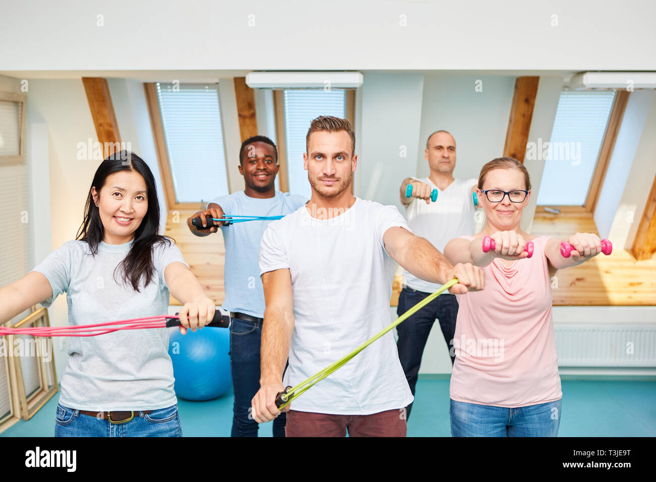 Groupe de jeunes sportifs à l'entraînement avec haltères courtes et extension in gym Banque D'Images