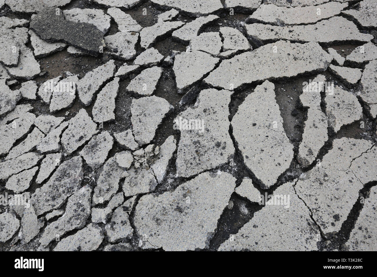 Fissures dans la route - les travaux de construction sur une route produisant des lignes intéressantes et des fissures dans le tarmac, représentée dans le West Sussex, Royaume-Uni. Banque D'Images