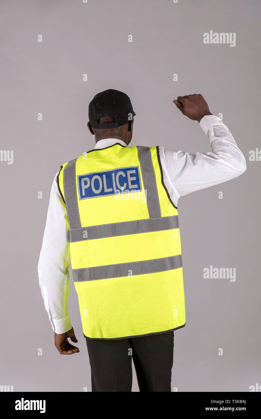 Salisbury, Wiltshire, UK, avril 2019. Vue arrière d'un agent de police de veste réfléchissante et le bras droit levé. Banque D'Images