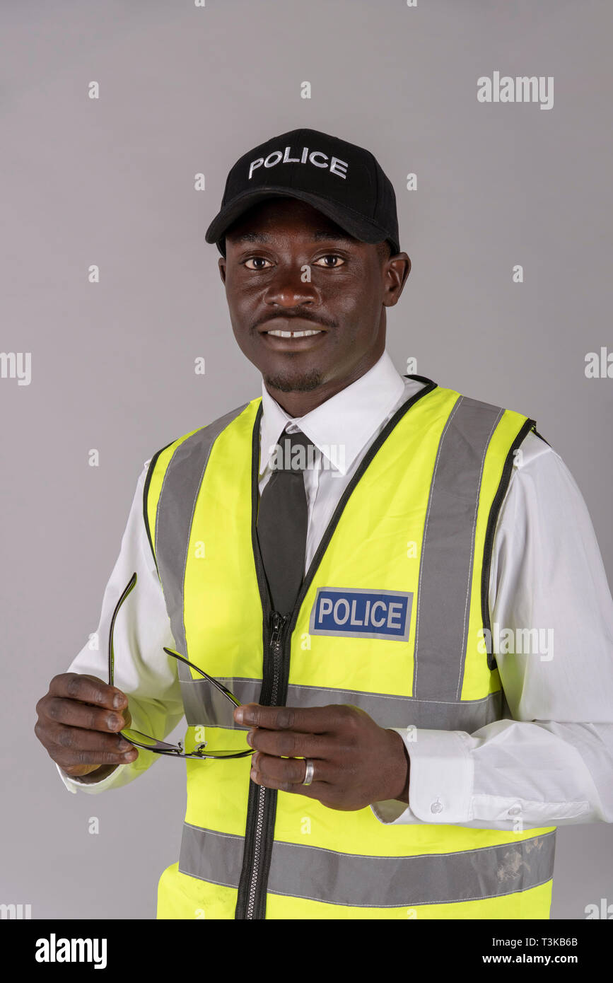 Portrait of a smiling agent de police en uniforme et tenant une paire de lunettes noires pour la protection des yeux. Banque D'Images