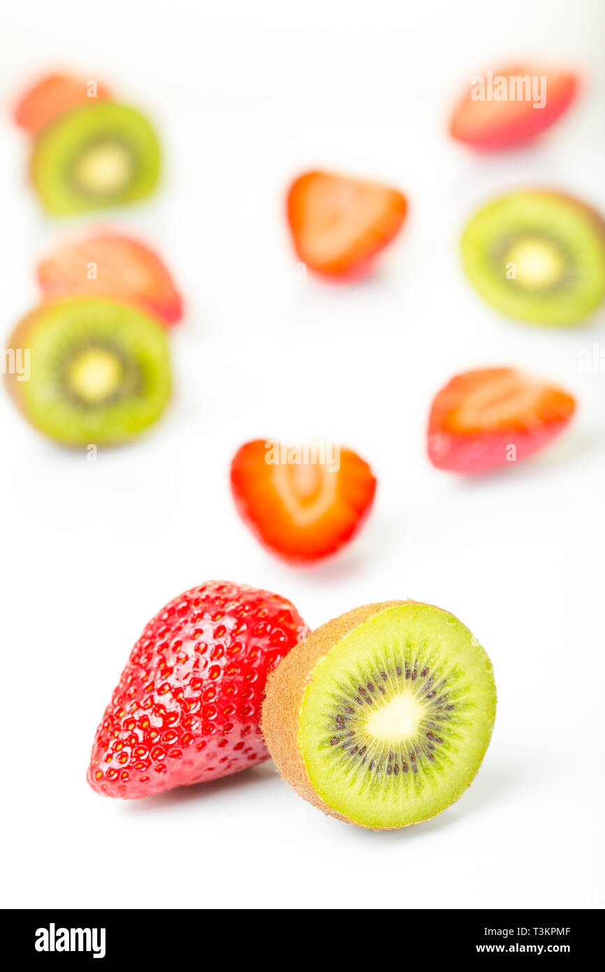Fraises rouge et vert kiwi coupé en moitié disposés sur un fond blanc. Banque D'Images
