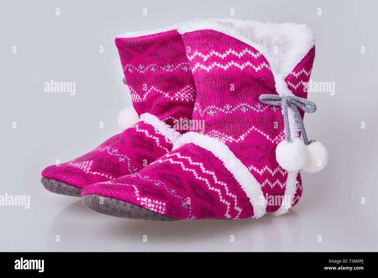Chaussons en tricot rose sur fond blanc. Chaleureuse maison confortable chaussons doux Banque D'Images