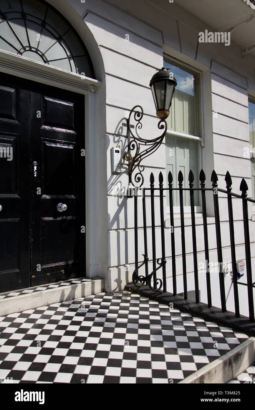 Porte avant de embourgeoisés Londres chambre avec entrée carrelé noir et blanc l'étape et garde-corps à l'autre Banque D'Images