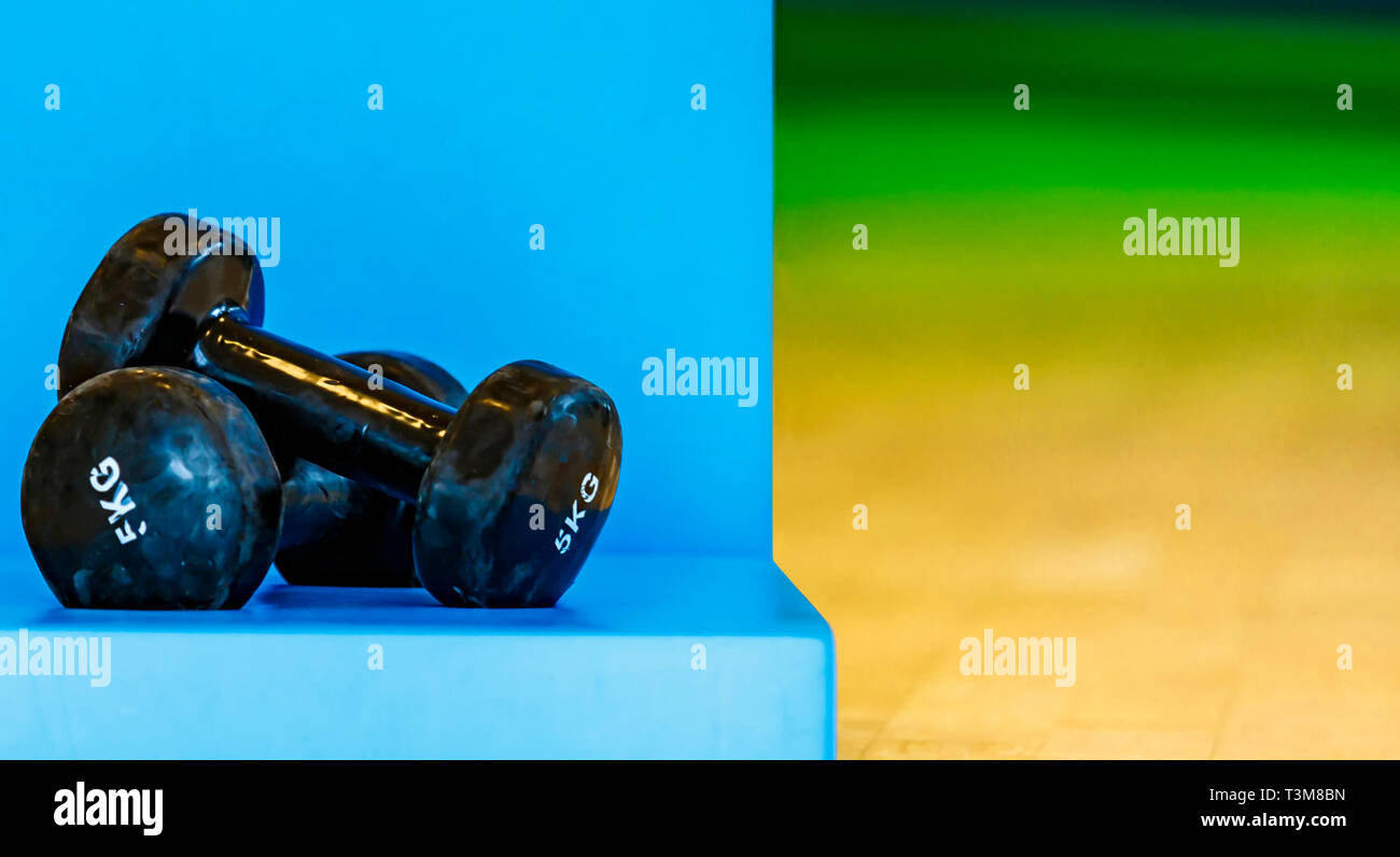 Pour l'aérobic haltères isolé noir et blondes sur un tapis bleu Banque D'Images