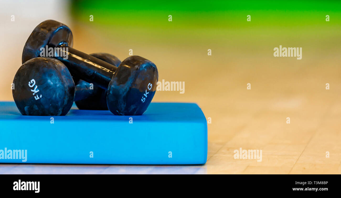 Pour l'aérobic haltères isolé noir et blondes sur un tapis bleu Banque D'Images