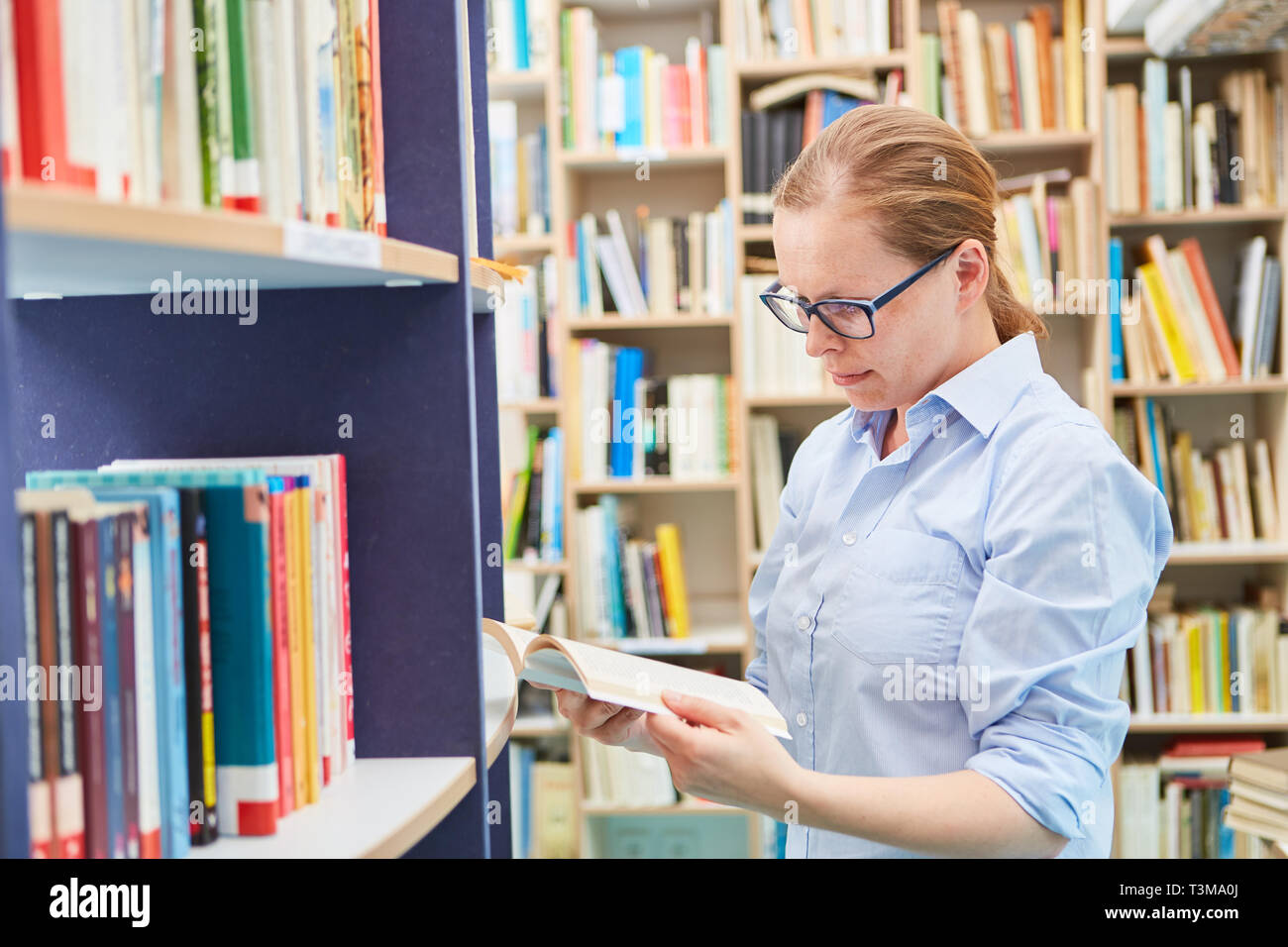 Femme recherche dans un livre dans la bibliothèque pour plus d'éducation et de la recherche Banque D'Images