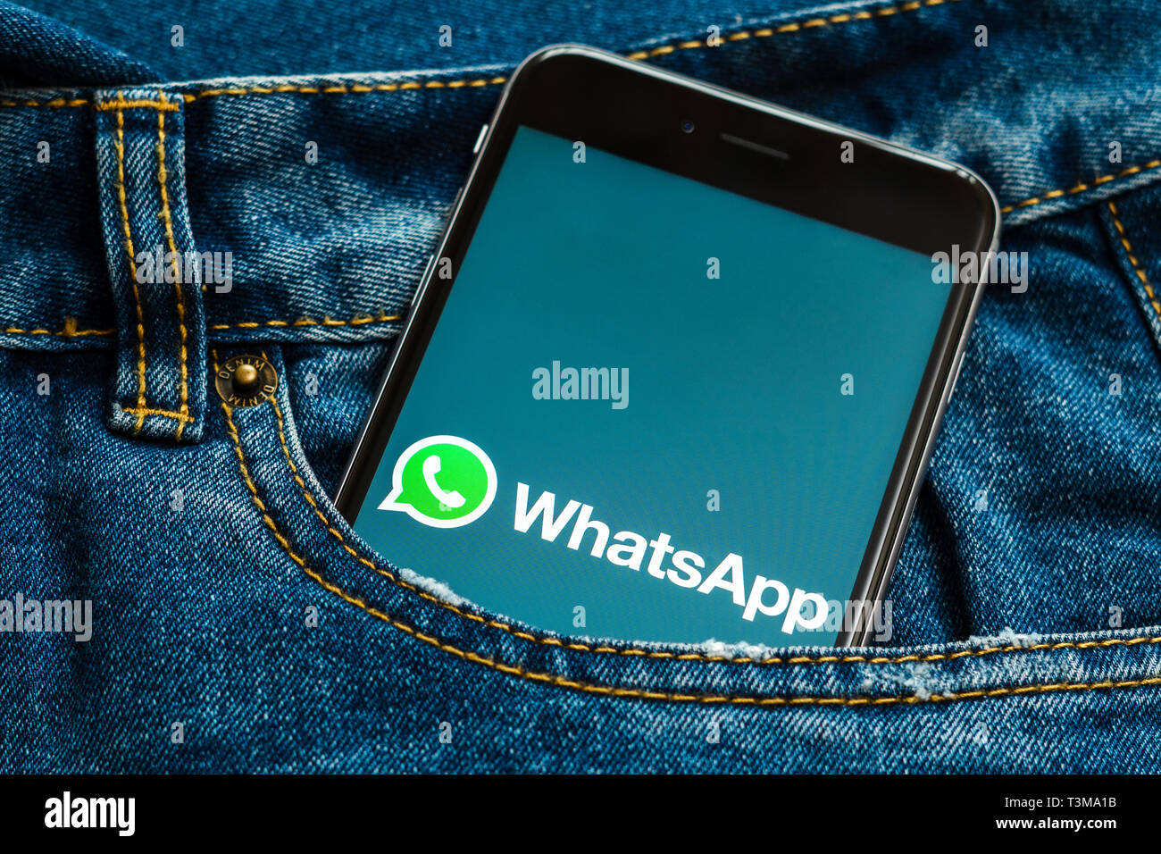 Téléphone noir avec logo des médias sociaux WhatsApp sur l'écran. L'icône des médias sociaux. Denim Jeans arrière-plan. Peut être utilisé pour le marketing ou business concept Banque D'Images