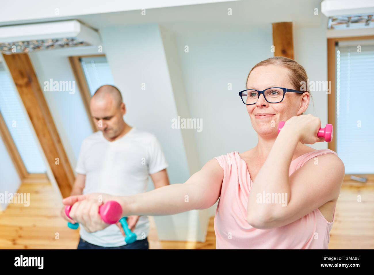 Jeune femme sportive avec haltères d'entraînement pour construire le muscle dans la salle de sport Banque D'Images