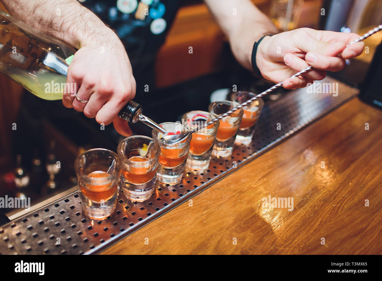 Bartender pouring strong boisson alcoolisée dans de petits verres sur bar, shots Banque D'Images