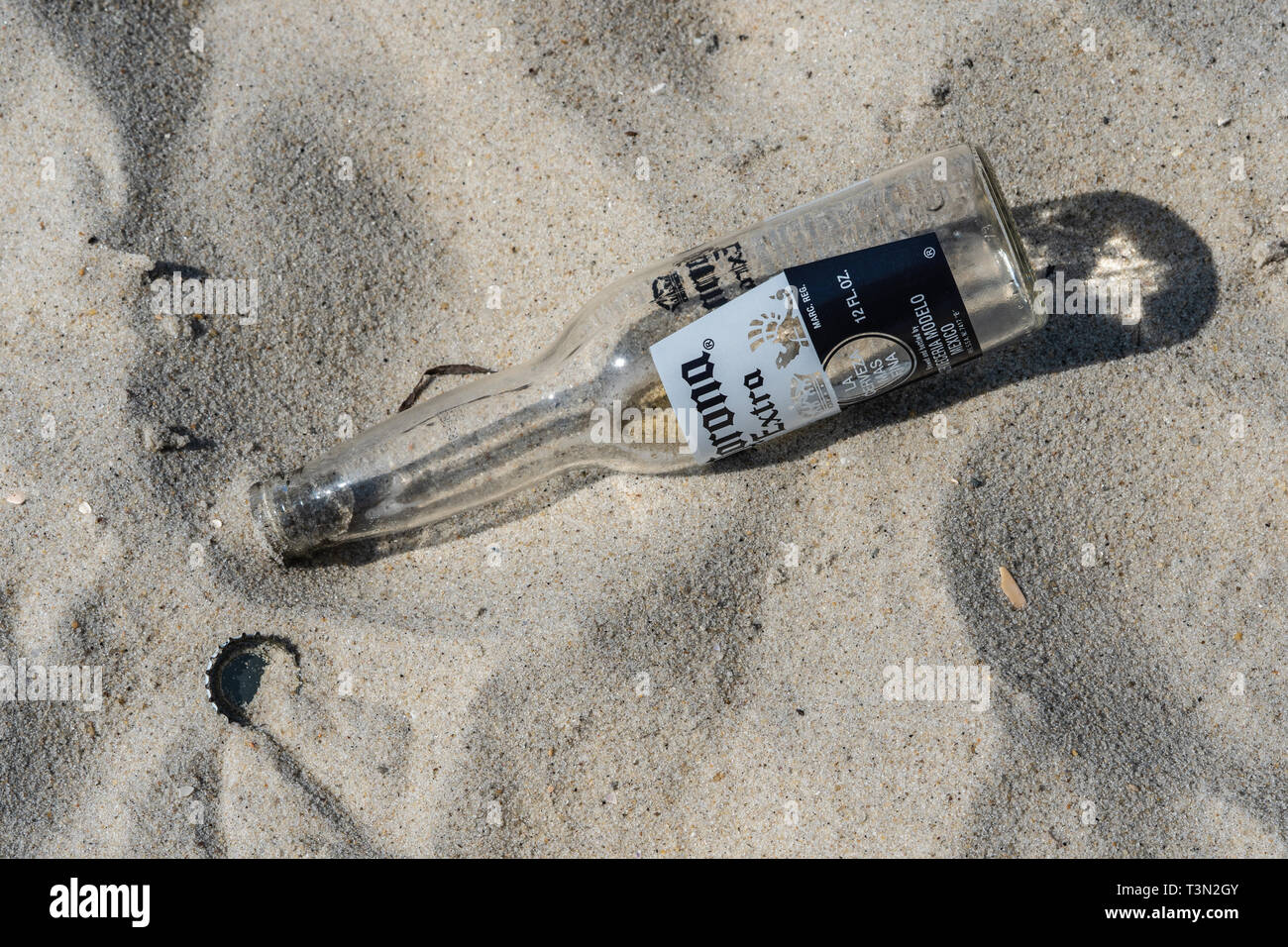 Wantaugh, NY - 21 août 2018 : Corona vide bouteille supplémentaire et le chapeau est abandonné dans le sable sur la plage à Jones Beach. Banque D'Images