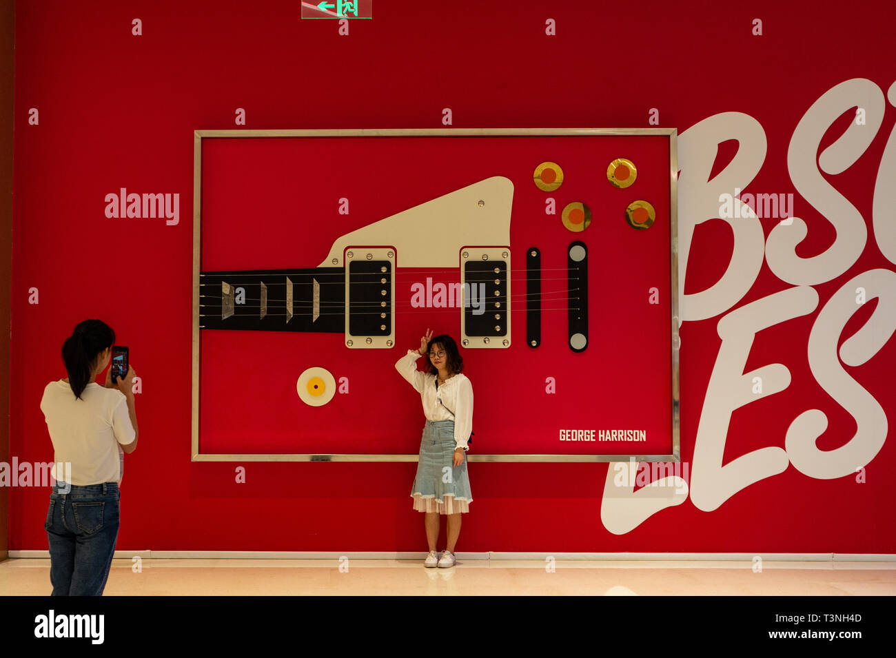 Visiteur pose pour la photo à côté de l'art moderne en forme de guitare pour une exposition Beatles à Shenzhen Chine Banque D'Images