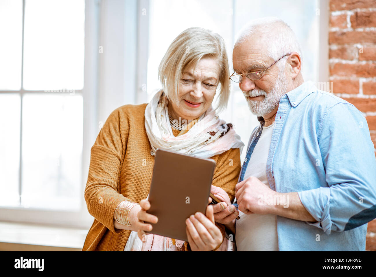 Belle senior couple Standing together près de la fenêtre à la maison Banque D'Images