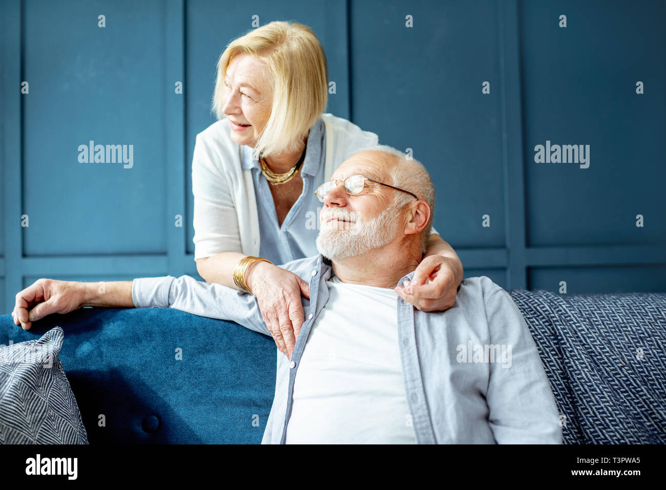 Portrait of a lovely couple habillé de Faire place au hasard ensemble sur le canapé à la maison sur le mur bleu Banque D'Images