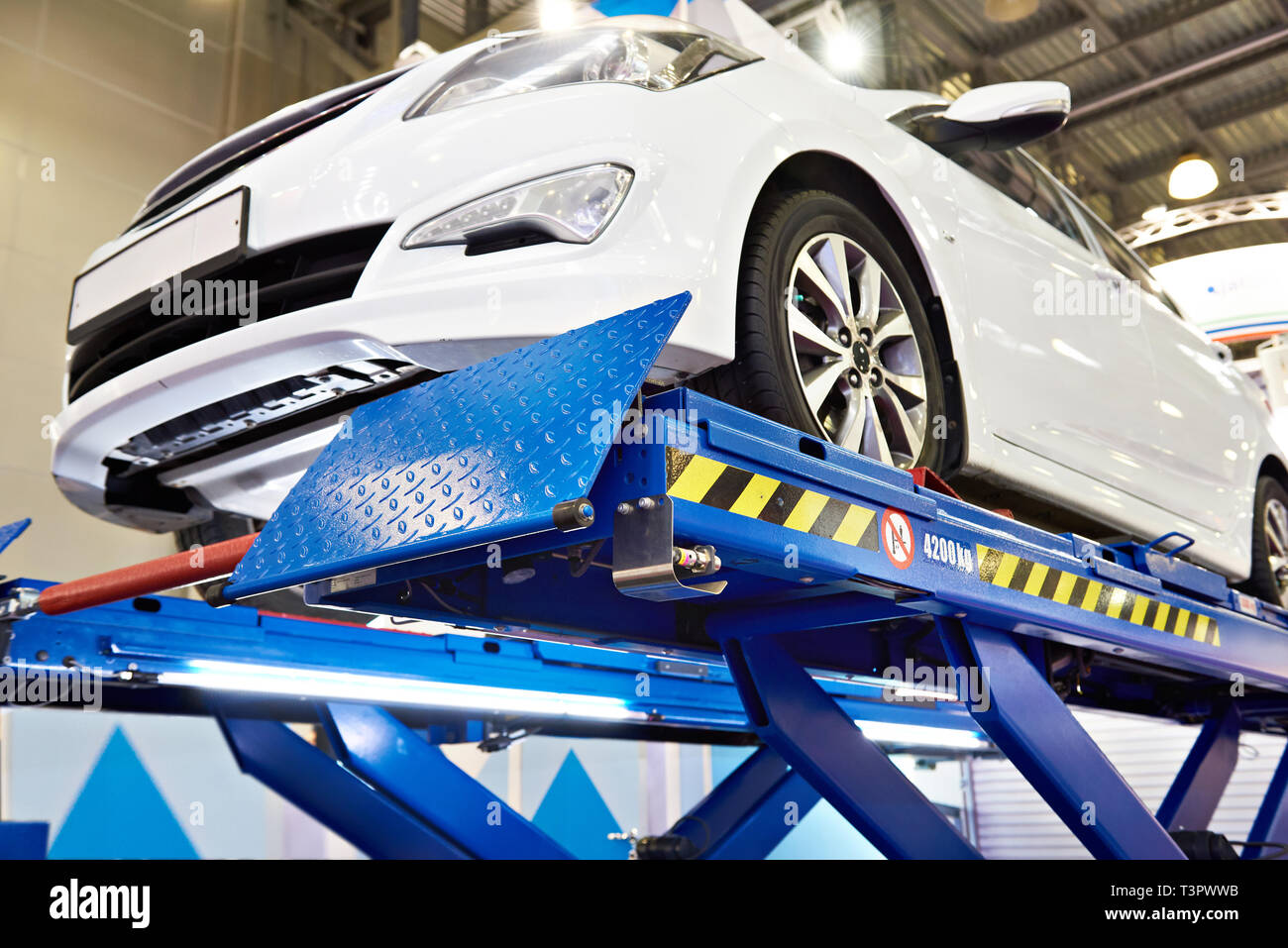 Voiture blanche sur l'ascenseur dans l'atelier de service auto Banque D'Images