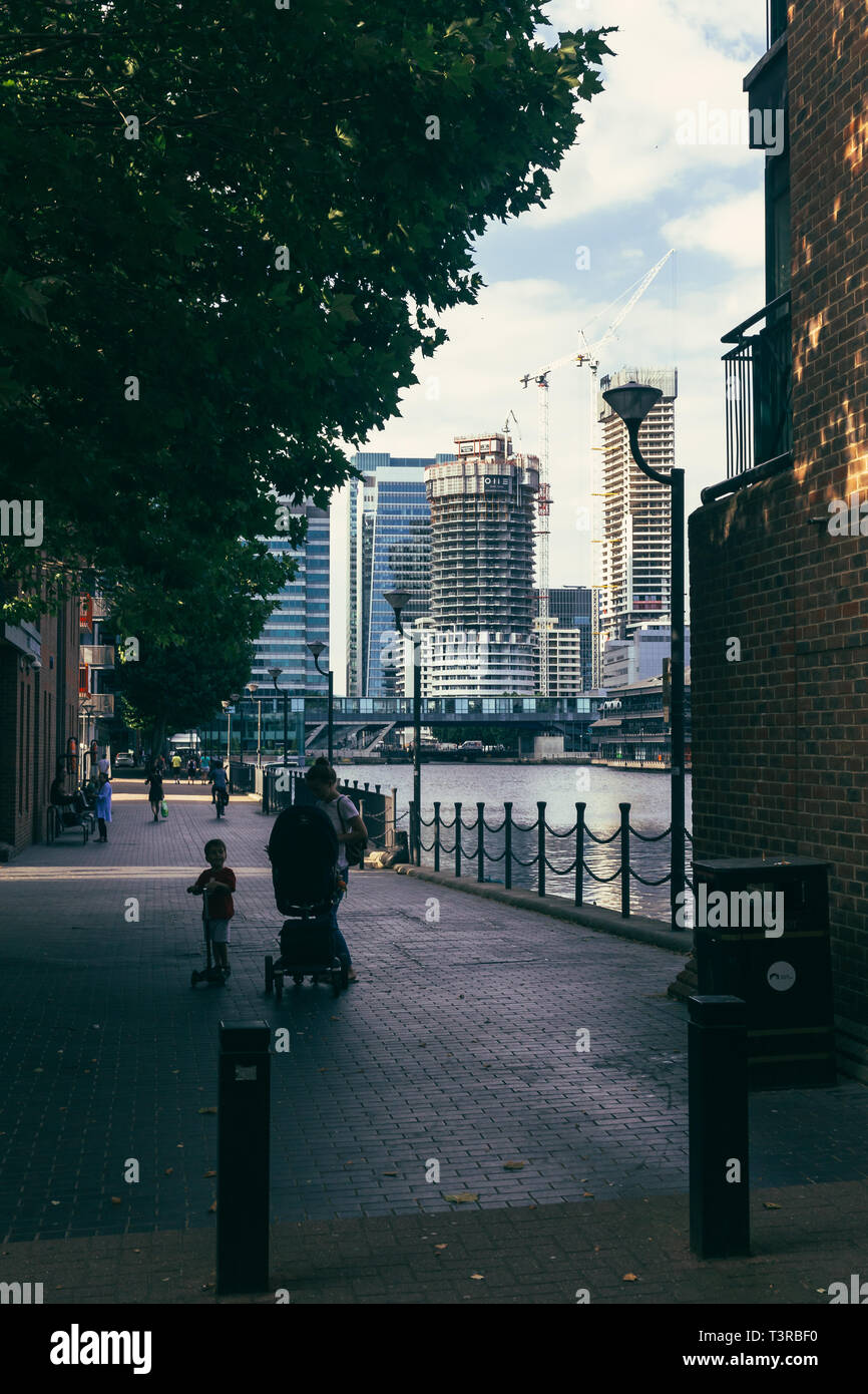 Londres, Royaume-Uni - 23 juillet 2018 : les gens marcher sur la rive de l'intérieur Millwall Dock, Canary Wharf gratte-ciel sur l'arrière-plan, Isle of Dogs Banque D'Images