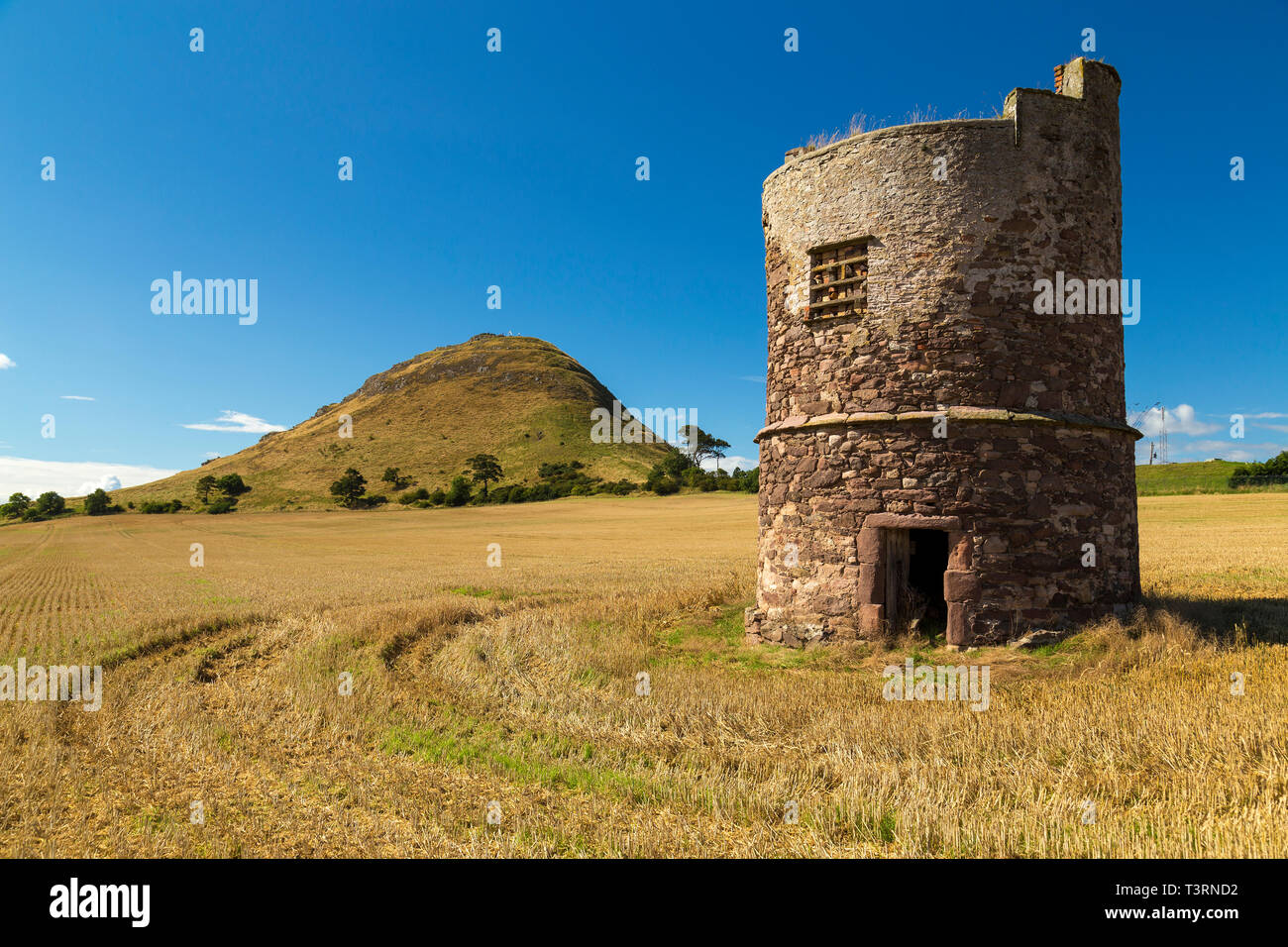 North Berwick droit dans un champ de chaume avec tour en pierre ancienne en premier plan. Banque D'Images
