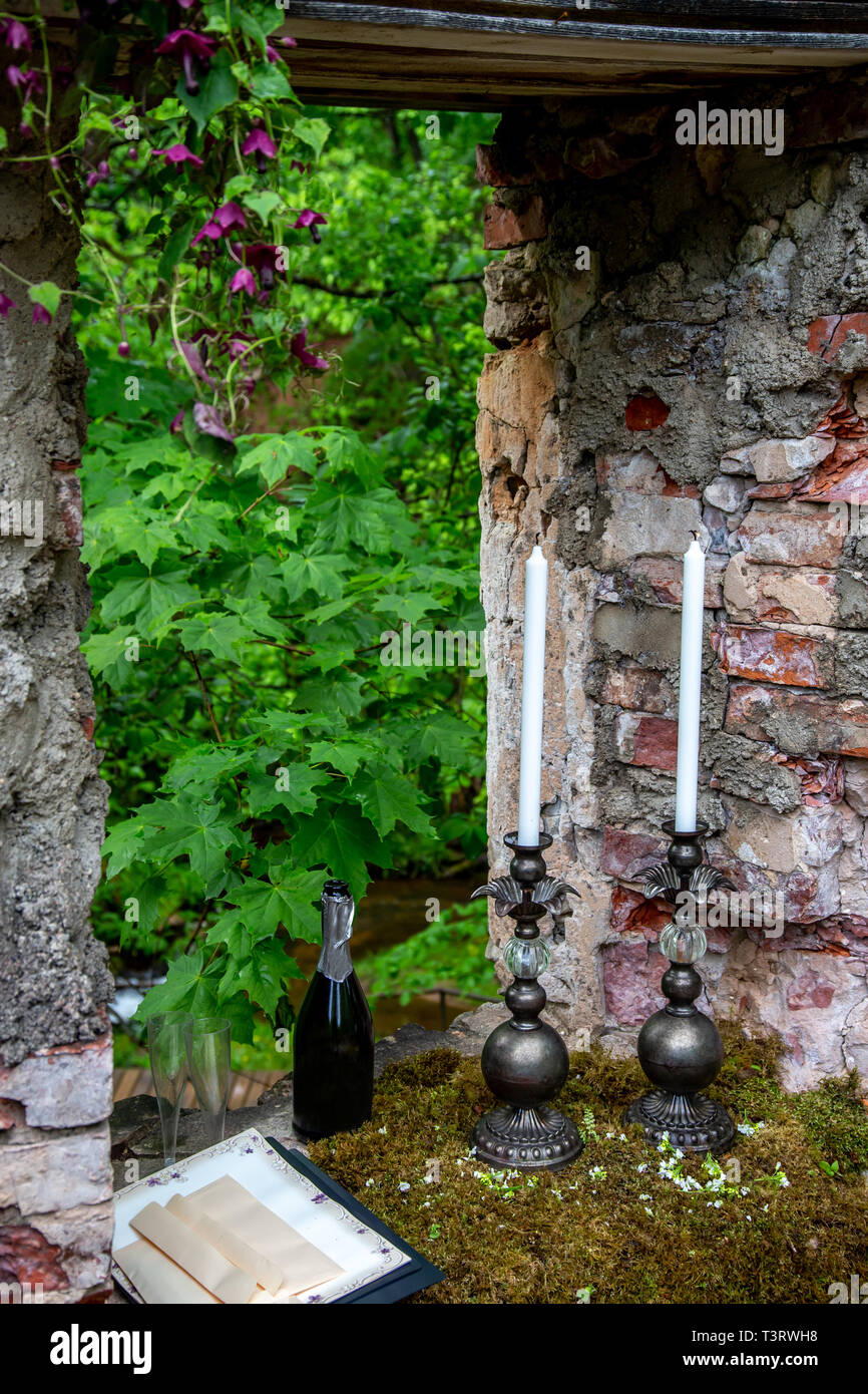 Bougies dans un chandelier, bouteille de champagne et deux verres de moss à vestiges de pierre. Célébration de mariage en caractères à l'extérieur. Banque D'Images