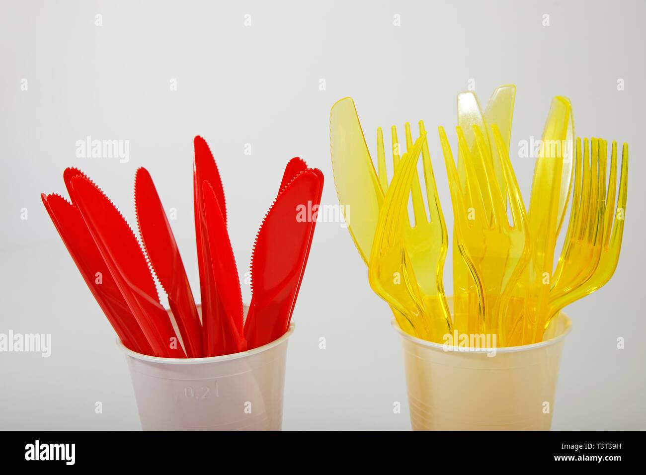 Couverts en plastique rouge et jaune dans des gobelets en plastique, le plastique couteaux, fourchettes en plastique, déchets de plastique, Allemagne Banque D'Images