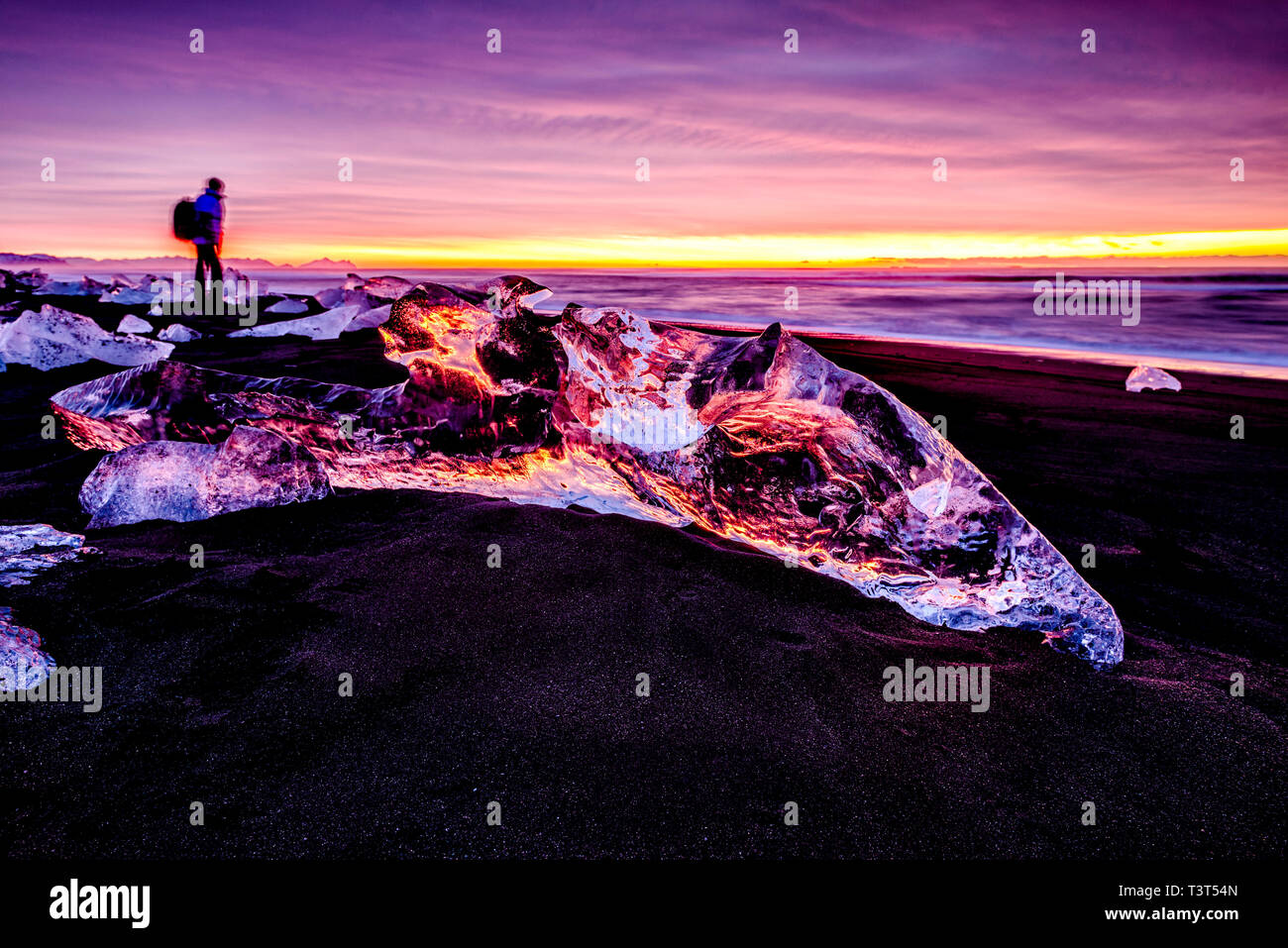 Randonneur admirant les glaciers sur beach reflétant sunset sky Banque D'Images