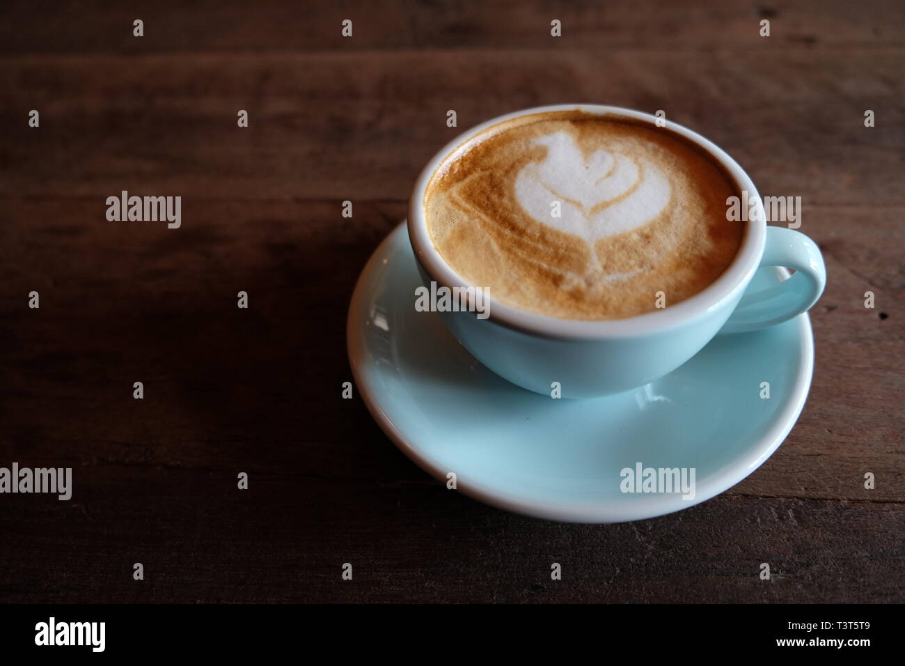 Cappuccino ou latte avec mousse écumeuse, blue Coffee cup top sur fond café en bois Banque D'Images
