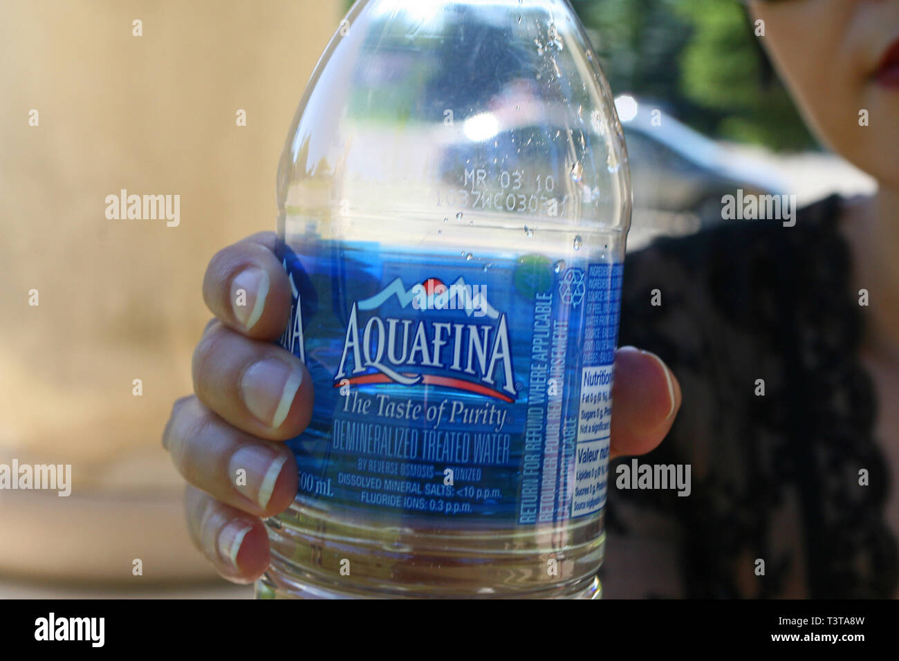 Belle jeune fille aux cheveux noirs sur une journée ensoleillée dans le parc ayant un verre d'eau purifiée. Banque D'Images