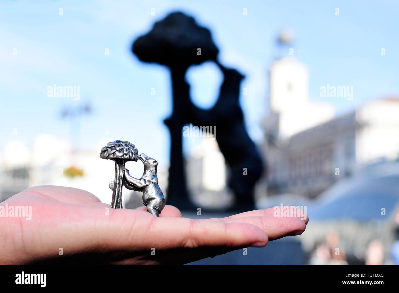 Quelqu'un qui tient un souvenir reproduction du monument populaire El oso y el Madrono avec le véritable monument à l'arrière-plan, à Madrid, Espagne Banque D'Images