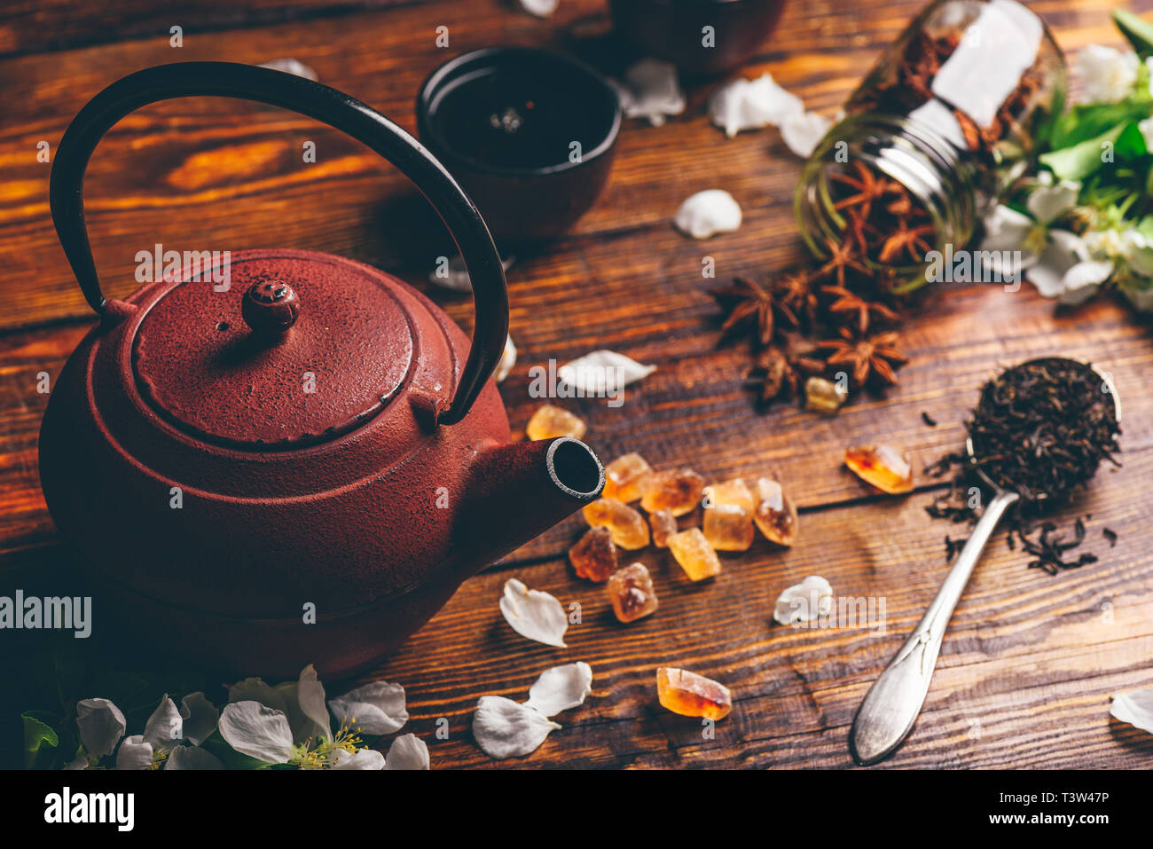 Théière avec cuillère de thé, de sucre et d'Apple Fleurs, étoile d'anis sur table en bois. Banque D'Images