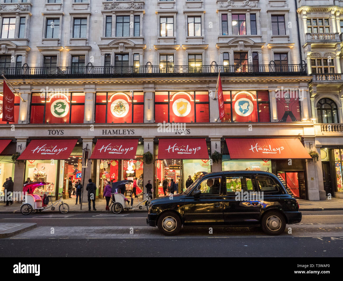 Des vélotaxis et traditionnel taxi stationné à l'extérieur de Hamleys Toy Store sur Regent Street, Londres, Angleterre. Banque D'Images