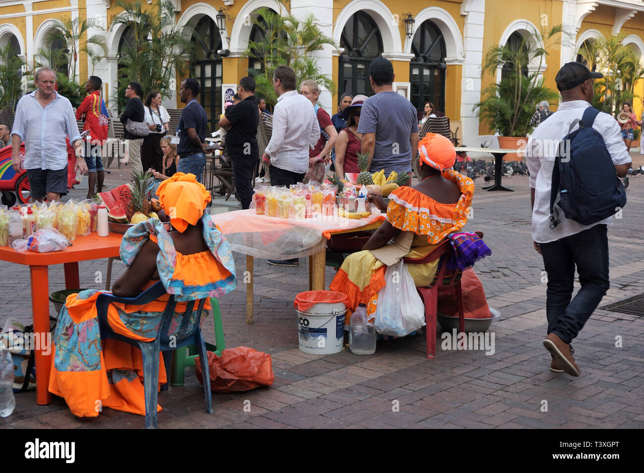 Vue arrière de deux Palenqueras en costume coloré assis à une table pleine de fruits tropicaux Banque D'Images