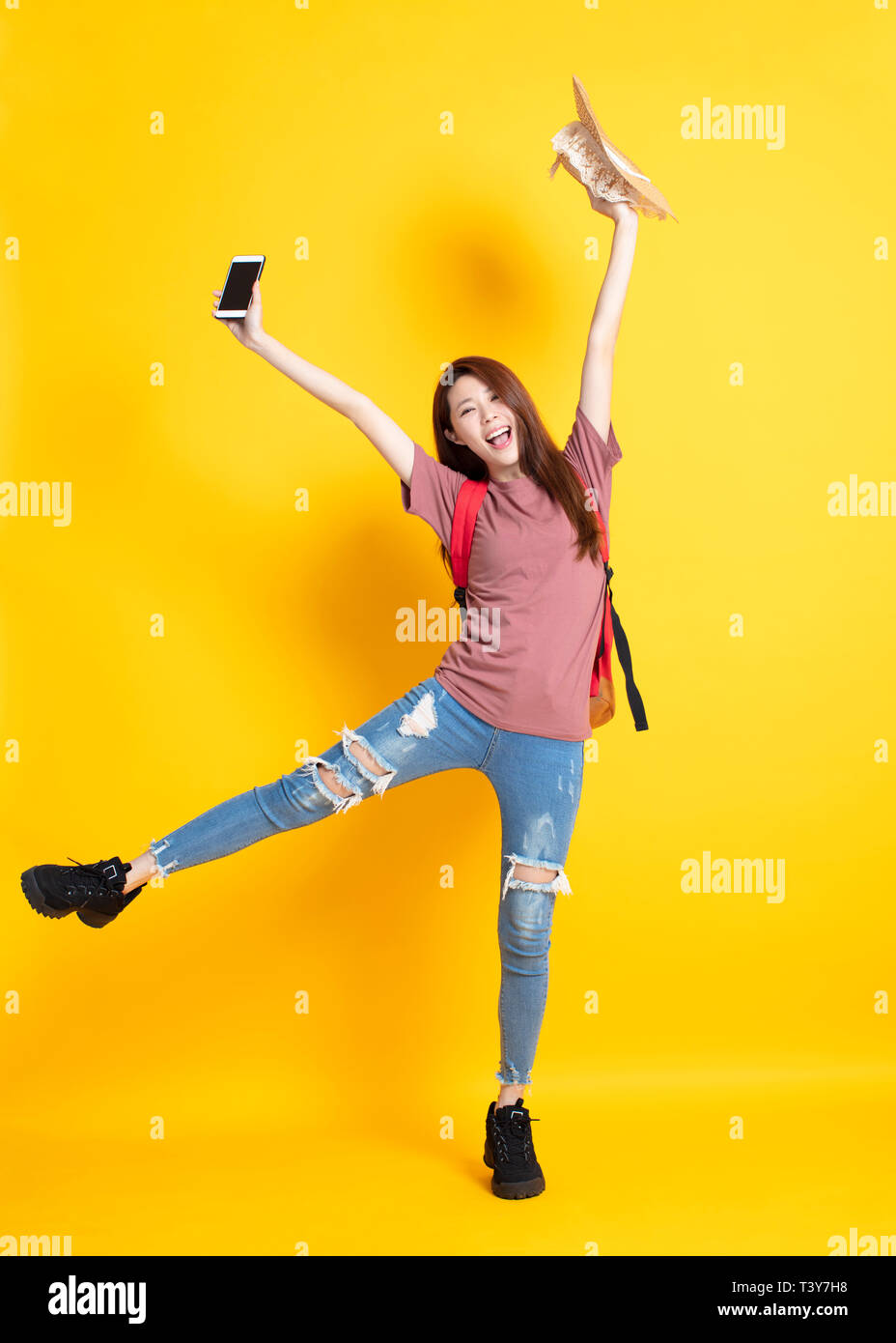 Happy young woman holding summer hat et montrant smart phone Banque D'Images