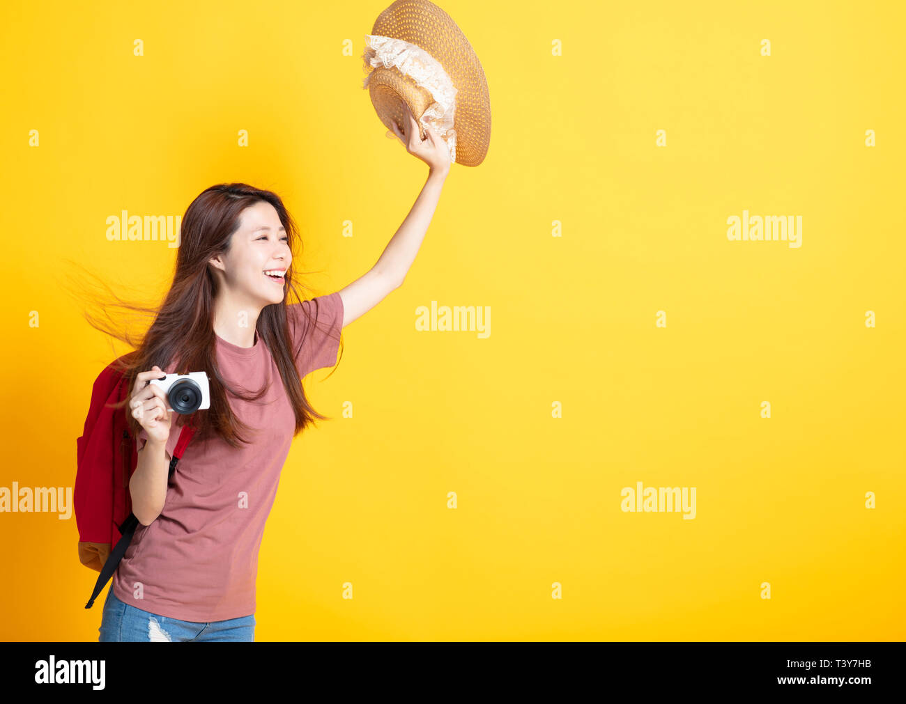 Happy young woman holding summer hat et caméra montrant Banque D'Images