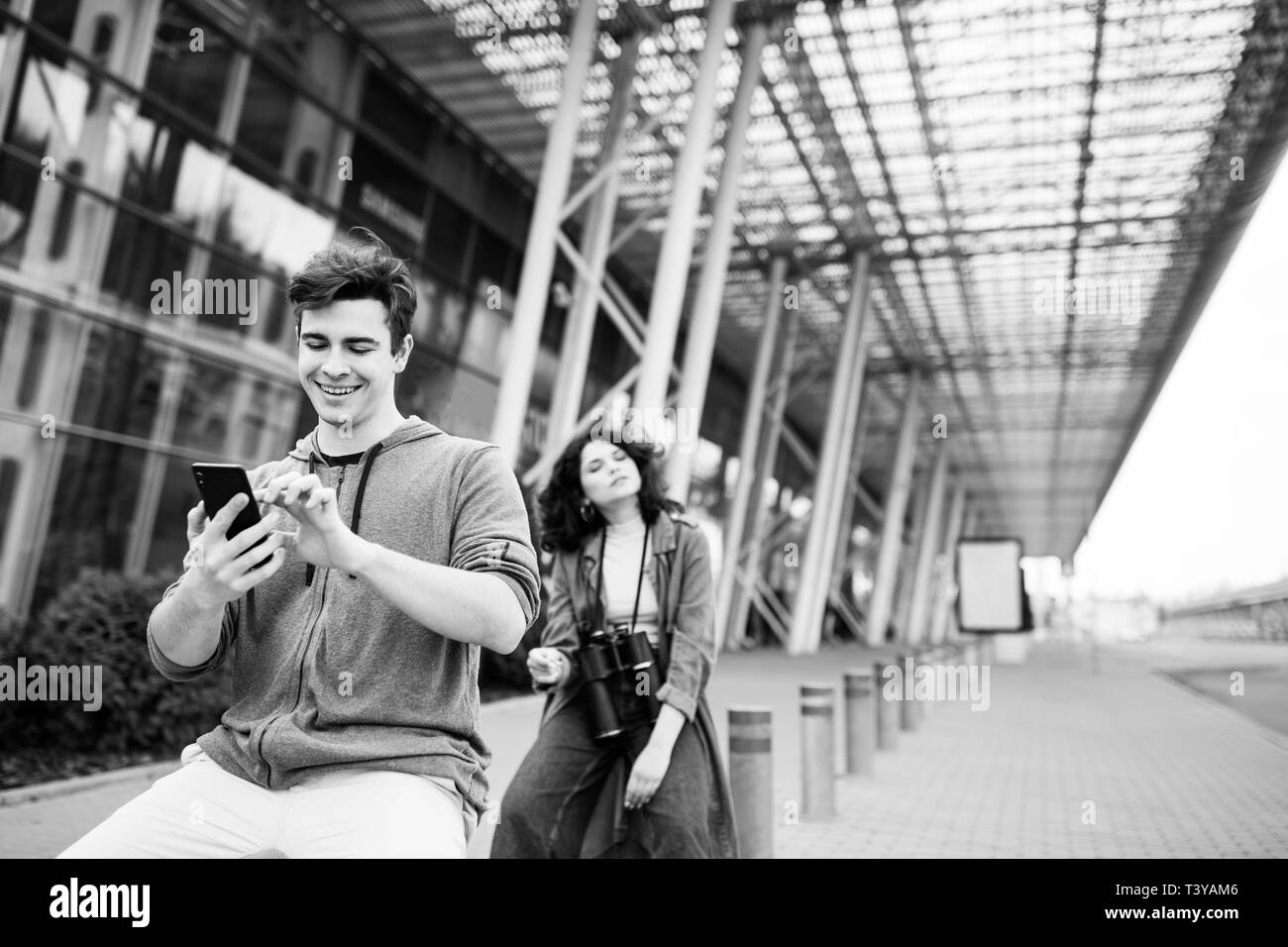 Le mec tient le téléphone dans ses mains. Jeune couple - un garçon et une fille dans la ville avec les jumelles dans leurs mains Banque D'Images