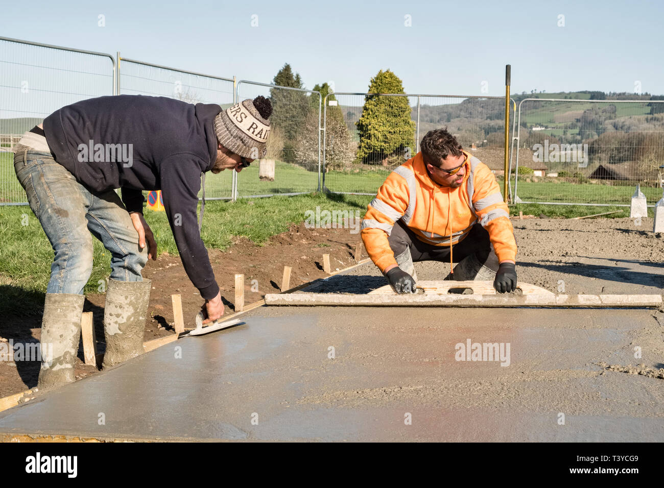 Presteigne, Powys, Wales, UK. Ouvriers à l'aide de flotteurs en béton pour lisser la surface d'un sol en béton fraîchement posées Banque D'Images