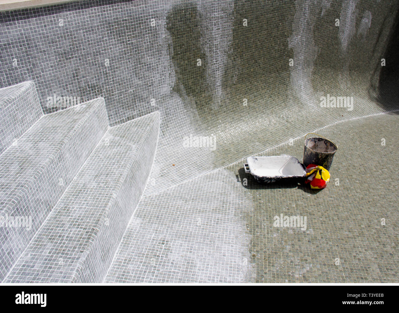 Le jointoiement du carrelage mosaïque en cours sur une fuite dans une piscine. Banque D'Images