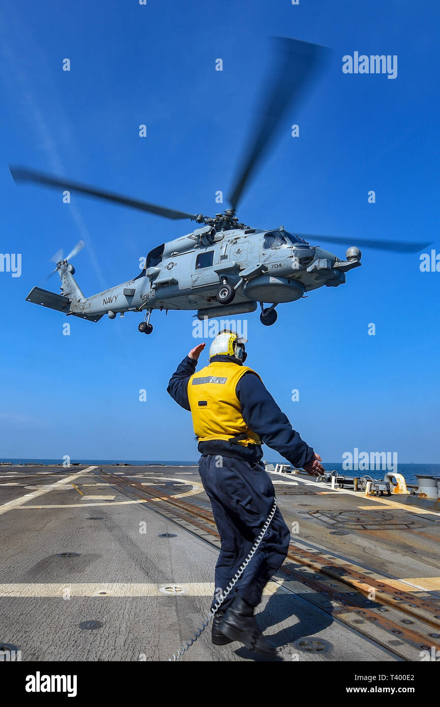 190411-N-JX484-418 MER DE HEBRIDES (avr. 11, 2019) Maître de Manœuvre 2e classe Eric Coleman dirige un MH-60R Seahawk hélicoptère des Spartiates de grève Maritime Squadron (70 HSM) hors de la cabine de pilotage à bord du destroyer lance-missiles USS gravement (DDG 107). Gravement sont en cours sur un déploiement de service comme le fleuron du 1er Groupe maritime permanent de l'OTAN à mener des opérations maritimes et fournir une capacité maritime continue de l'OTAN dans le nord de l'Atlantique. (U.S. Photo par marine Spécialiste de la communication de masse 2e classe Mark Andrew Hays/libérés) Banque D'Images