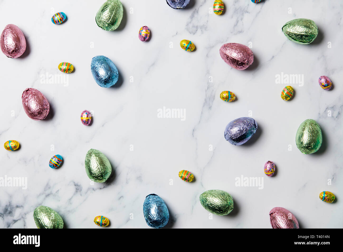 Gâteries au chocolat oeufs de pâques enveloppés de papier métallique de couleur brillant sur fond de marbre Banque D'Images