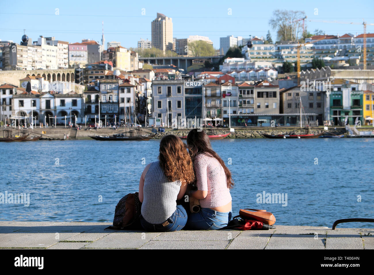 Deux jeunes femmes siégeant ensemble manger sur le quai à la recherche de l'autre côté de la rivière Douro, à Vila Nova de Gaia à Porto, Portugal Europe KATHY DEWITT Banque D'Images