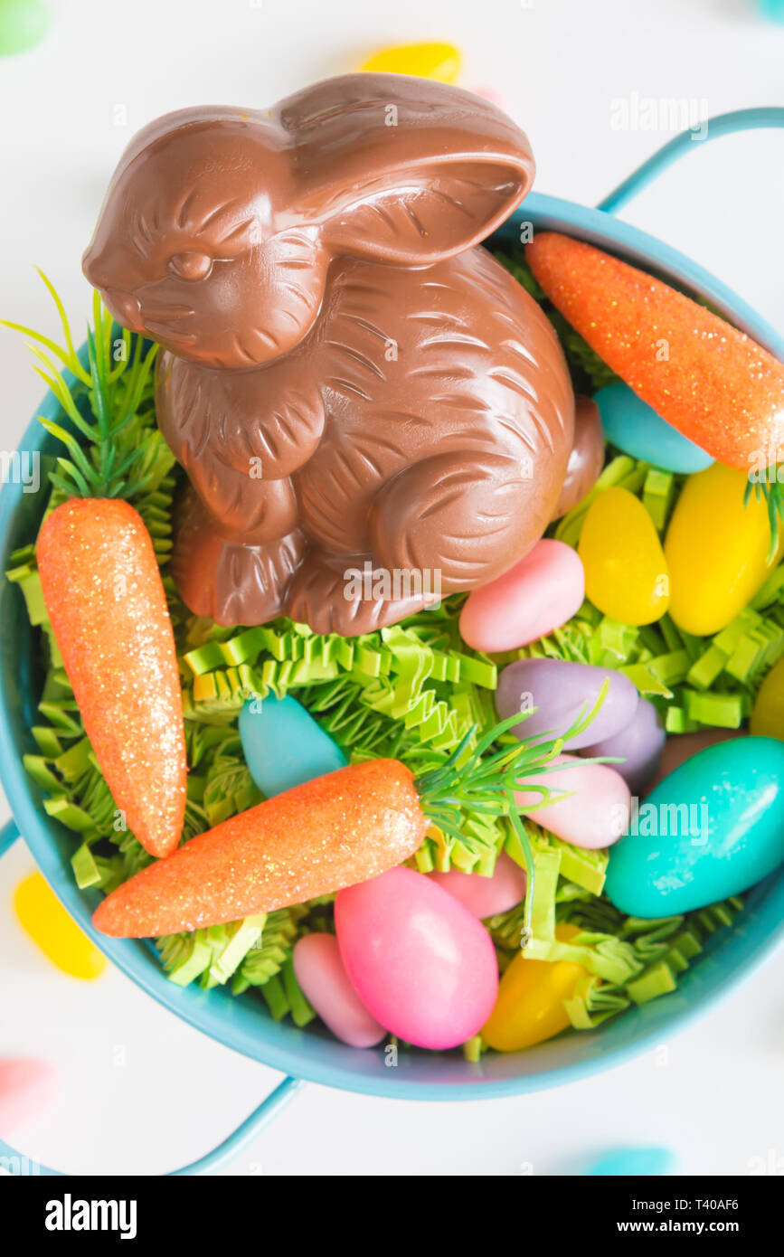 Close-up du chocolat lapin de Pâques dans Easter basket avec mini-carottes et les bonbons oeufs sur fond blanc Banque D'Images